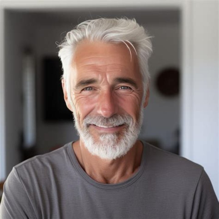a man with white hair pointing to the side and holding his finger up in