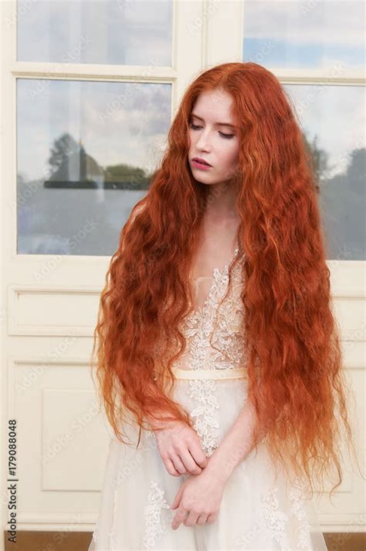 a woman with red hair wearing a pink dress and looking off to the side